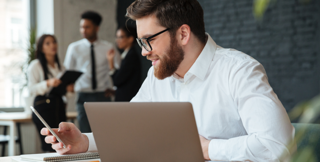 Profissional analisando smartphone e notebook ao escolher uma solução de MDM para empresa