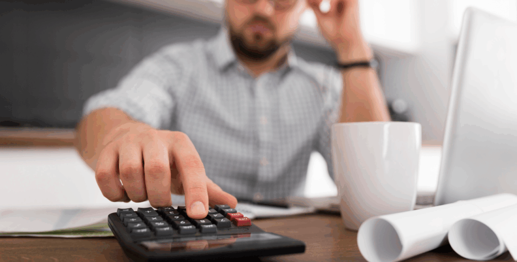 Profissional analisando custos com calculadora e laptop, representando a redução de despesas empresariais com o uso do MDM.