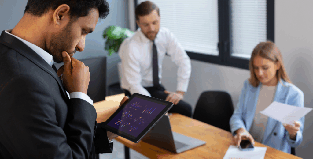 Profissional analisando dados em um tablet durante reunião de trabalho, representando a integração entre MDM e ITAM na gestão de dispositivos móveis corporativos.