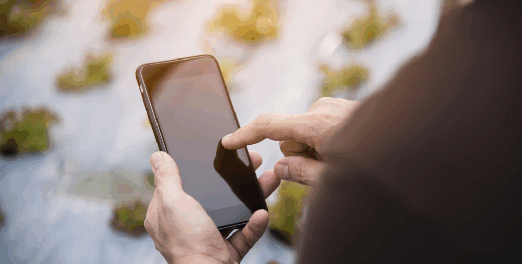 Pessoa utilizando smartphone em ambiente externo, simbolizando o uso sustentável de dispositivos móveis com apoio do MDM.