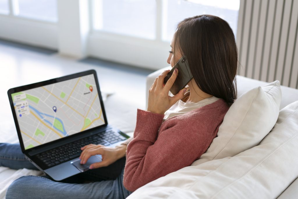 Mulher usando notebook com mapa para monitoramento por geofence enquanto fala ao telefone
