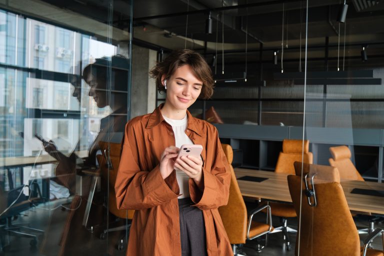 Profissional usando um celular corporativo dentro do escritório para atividades de trabalho