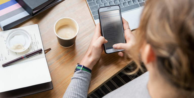 Profissional utilizando iPhone corporativo no escritório com acesso a aplicativos empresariais gerenciados por Apple MDM