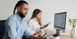 Profissionais utilizando dispositivos corporativos em ambiente de trabalho, representando o modelo CYOD (Choose Your Own Device) para uso de celulares e computadores na empresa.
