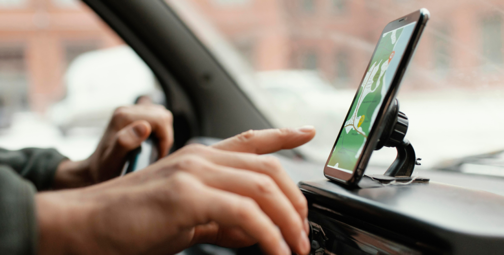 Motorista utilizando celular ao volante, ilustrando o bloqueio de tela por velocidade para aumentar a segurança com MDM