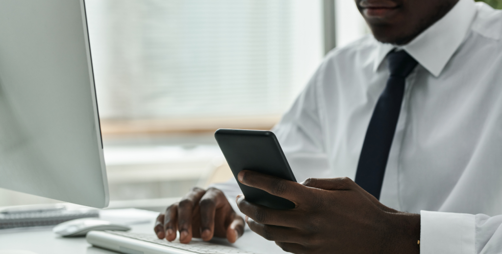 Profissional utilizando celular corporativo no trabalho, representando o monitoramento de celular corporativo para controle e segurança dos dispositivos.