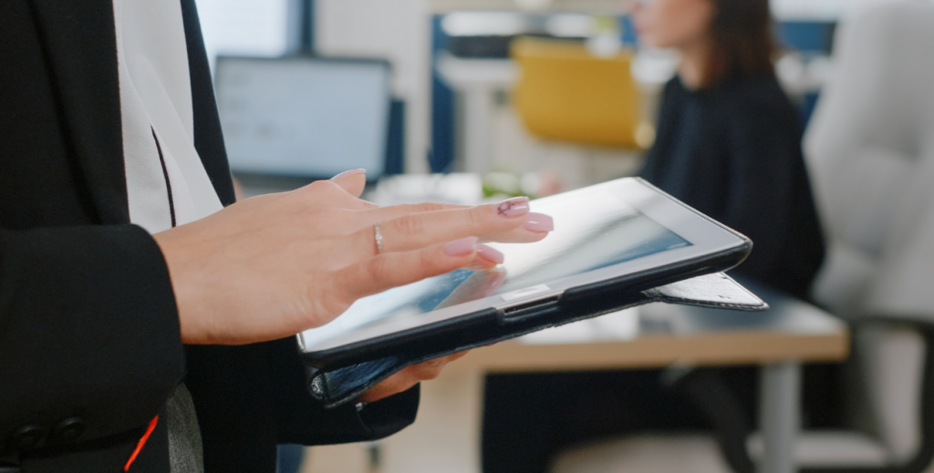 Colaborador utilizando tablet compartilhado em ambiente corporativo, representando a gestão de dispositivos compartilhados em equipes e áreas comuns