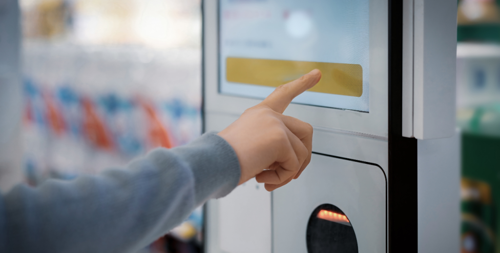 Usuário interagindo com totem de autoatendimento com tela touchscreen, representando a gestão de totens de autoatendimento em ambientes comerciais